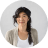 A smiling woman with long dark hair styled in a braid, wearing a light cardigan, against a neutral background.
