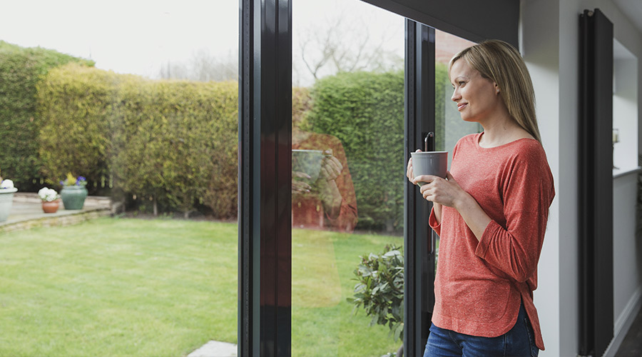 woman holding a mug and looking out large windows taylorsville ut